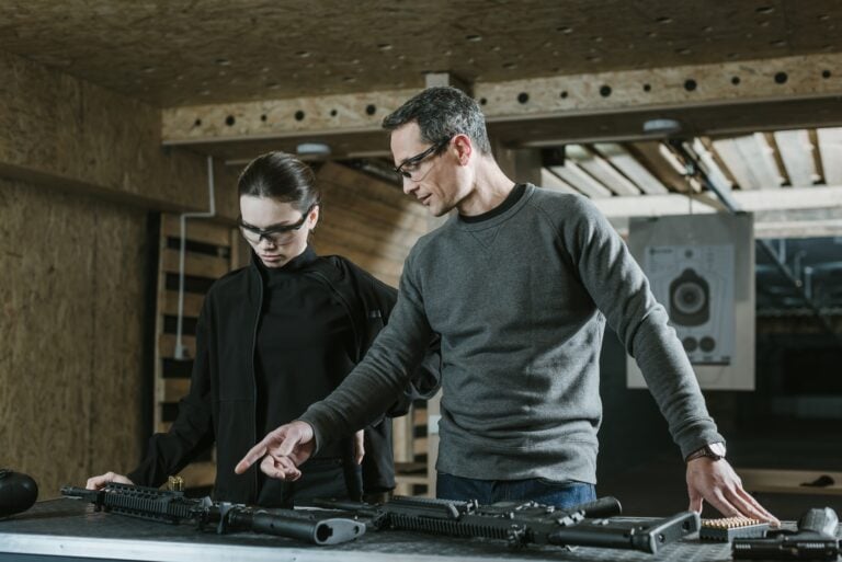 Certified gun instructor guiding a student through firearm safety training at an indoor shooting range