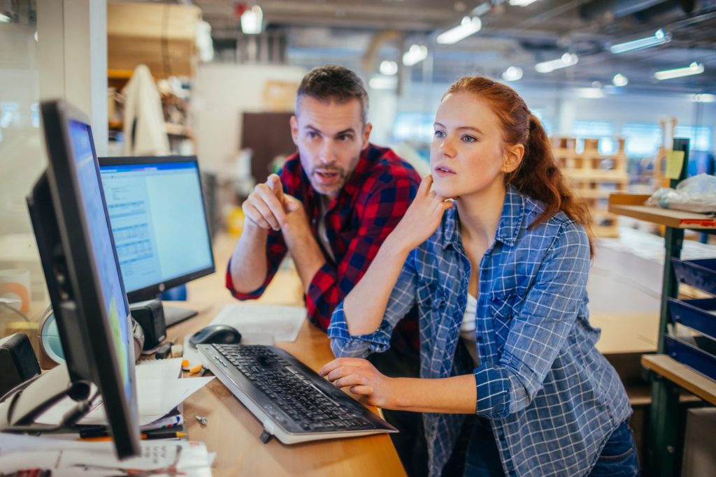 Two professionals collaborating at a computer to analyze AI search vs SEO data and bridge the prompt gap for JAR Consulting Group.
